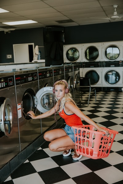 一名妇女跪在洗衣店内的前洗衣机前